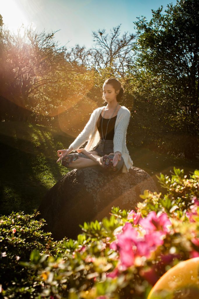 A woman meditating outside in nature practicing self-care